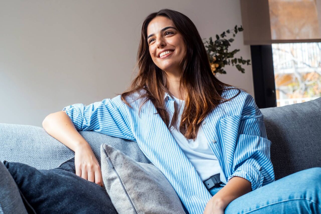 Young smiling woman in therapist’s office representing the benefits of finding the right mental health provider.
