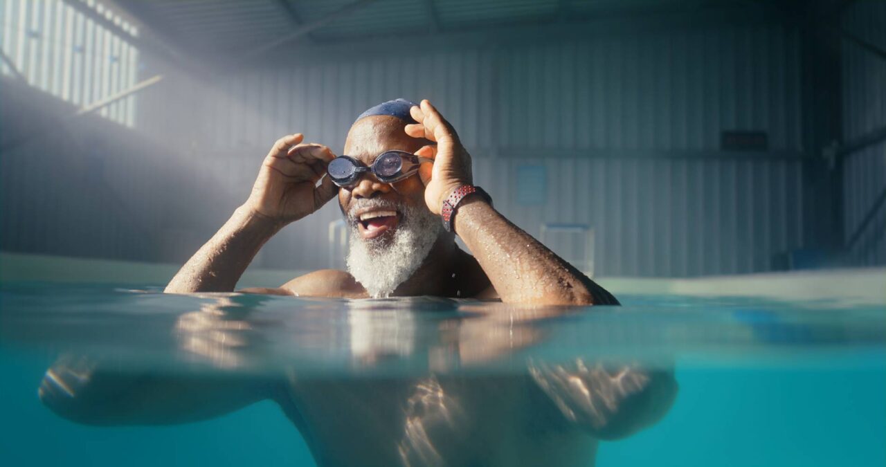Senior, black man adjusting goggles in swimming pool for relaxation and mental health