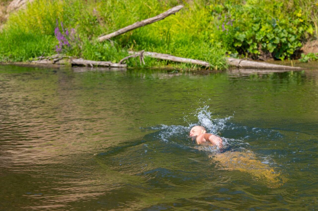 A man swims in a wild river for relaxation and mental health.